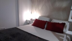 A bed with a white headboard, a red pillow, and a dark blanket. - Encanto Cuenca - Weather Bridge (Cuenca)