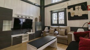 Ein modernes Wohnzimmer mit Flachbildfernseher, einer Couch, einem Couchtisch und einem Kamin.