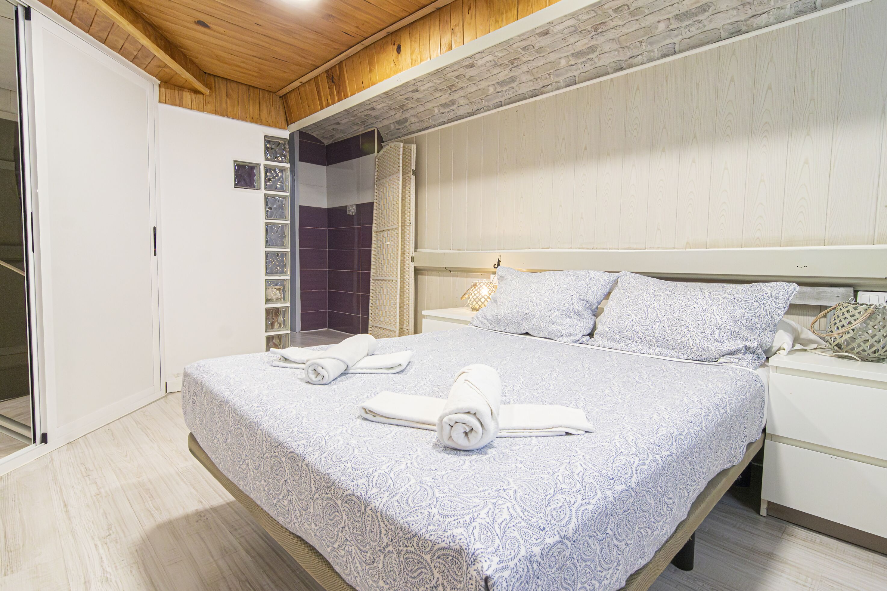 Un dormitorio con una cama grande, una mesita de noche y un armario.