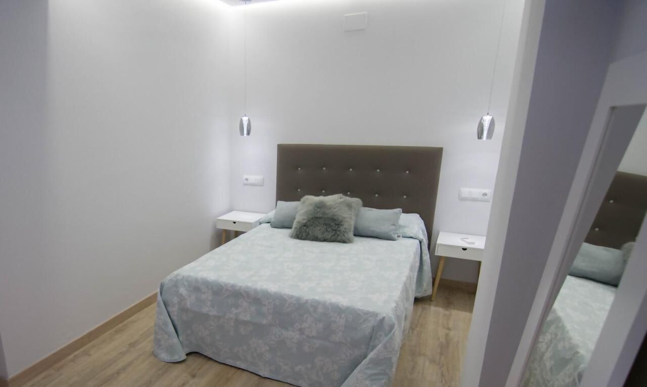 Un dormitorio con cama, mesitas de noche y un espejo.