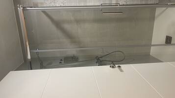 Un bagno moderno con box doccia in vetro, lavandino bianco e schienale rivestito di piastrelle decorative.