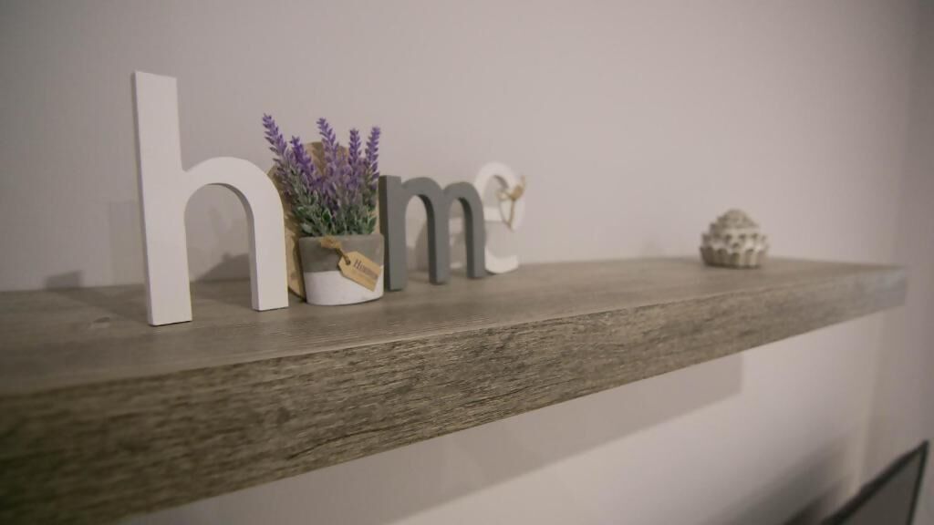 A wooden shelf with decorative items including letters spelling "home," a small potted plant, and a decorative object.
