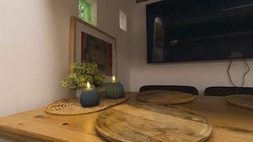 Ein Holztisch mit Tischsets, Kerzen und einem kleinen Topfpflanzen.