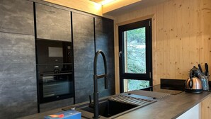 A modern kitchen with dark cabinetry, a stainless steel sink, and a window providing a view of the outdoors. - Superior Chalet With Sauna and hot tub (Stadl-Predlitz)