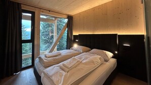 A bedroom with two beds, a large window, and a view of trees. - Superior Chalet With Sauna and hot tub (Stadl-Predlitz)