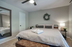 Relax in this serene bedroom with a large bed, mirror, and comfortable seating area.