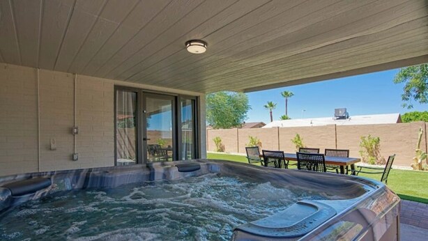 A hot tub area with a covered patio, outdoor seating, and a view of the backyard. - Modern Tempe Retreat w/Hot Tub

 (Tempe)