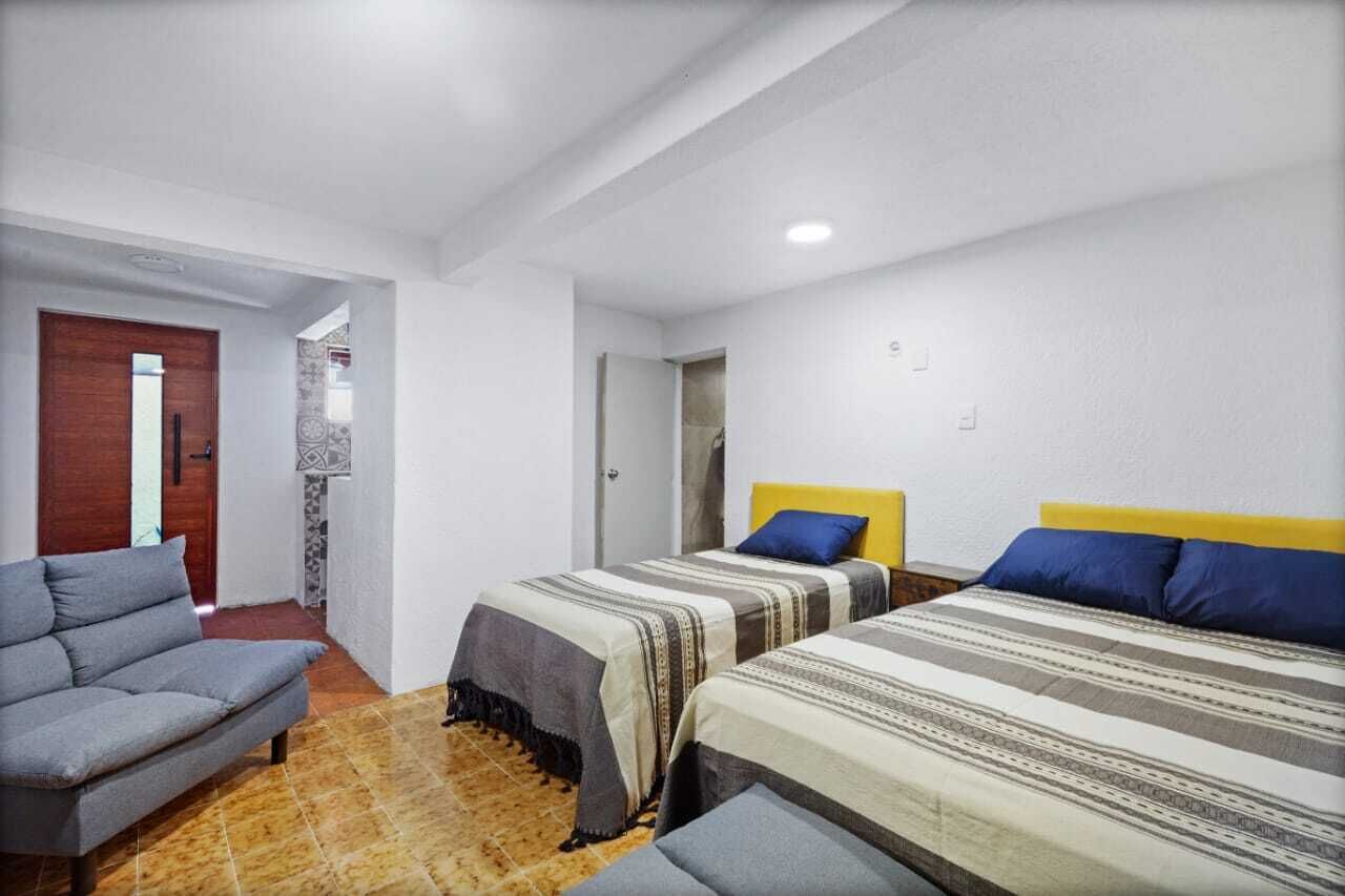 Ein Zimmer mit zwei Betten, einem Schlafsofa und einer Tür zu einem anderen Raum.