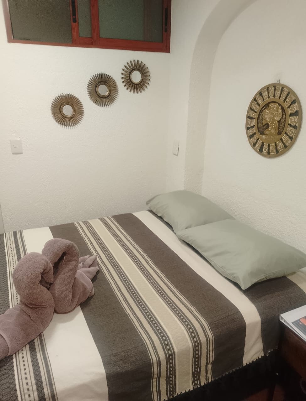 A bedroom with a bed, pillows, a blanket, and decorative wall art.