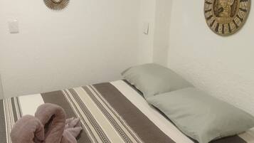 A bedroom with a bed, pillows, a blanket, and decorative wall art.