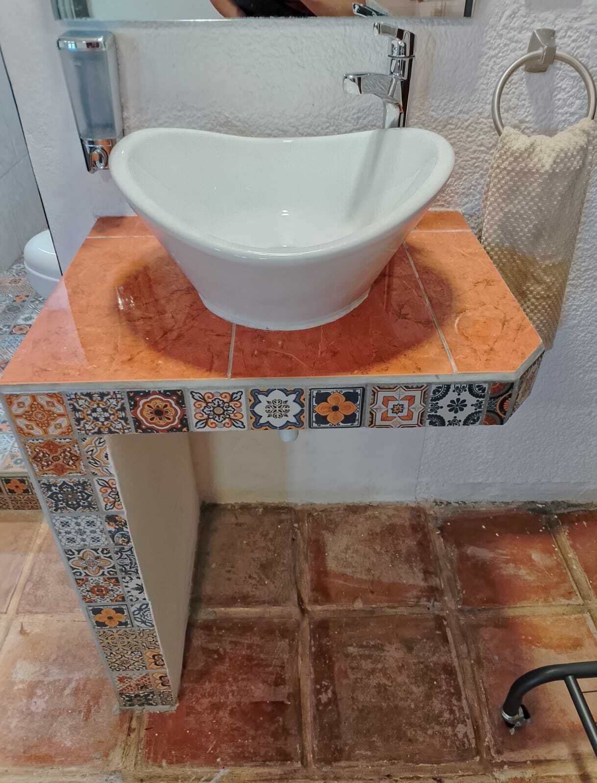 A bathroom with a white sink on a tiled countertop, a towel ring, and a toilet.
