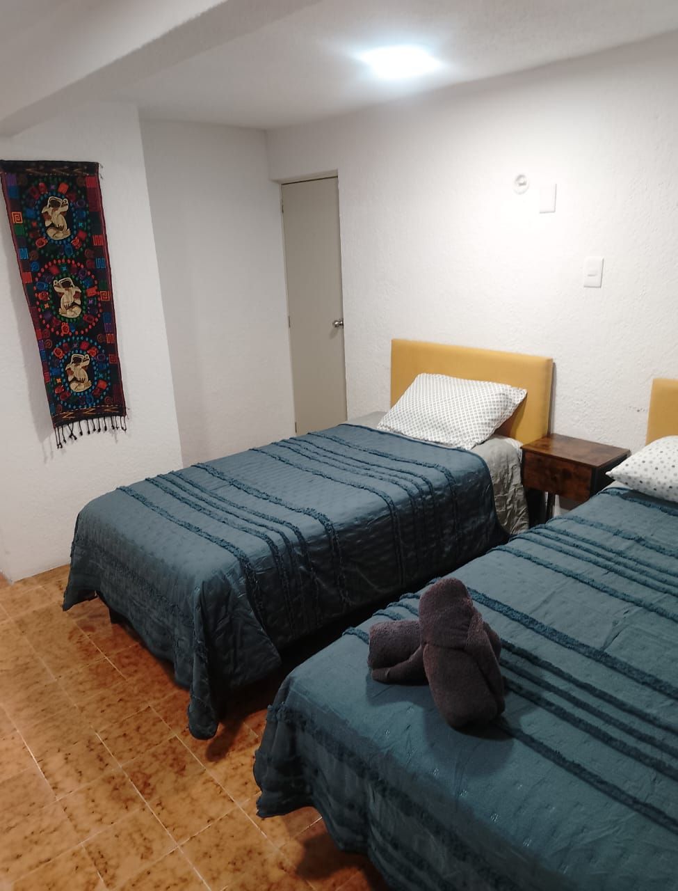 A room with two beds, a door, and a wall hanging.