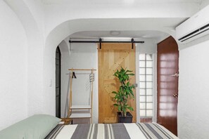 Un dormitorio con una cama, una puerta de madera, una planta en maceta y una ventana con vistas.
