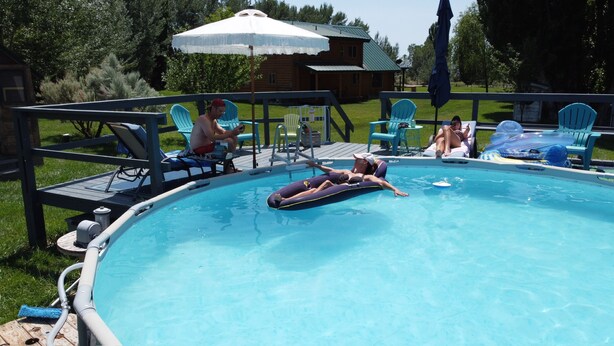 A swimming pool with lounge chairs and umbrellas. - Cozy Ranch Apartment, perfect for hunting season, or a fun weekend getaway. (Winnemucca)