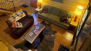 A cozy cabin interior with a wooden ceiling, a sofa, a couch, a coffee table, and a fireplace. - Cozy Ranch Apartment, perfect for hunting season, or a fun weekend getaway. (Winnemucca)