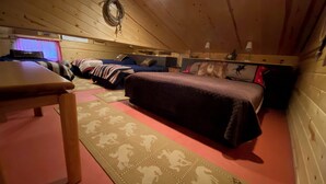 A cozy cabin room with a bed, a table, and a hanging light fixture. - Cozy Ranch Apartment, perfect for hunting season, or a fun weekend getaway. (Winnemucca)