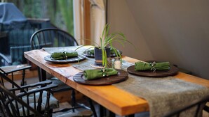Een houten eettafel gedekt met borden, een potplant en groene servetten.