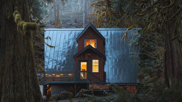 Een chalet met houten gevel, een balkon en een raam met warme verlichting.