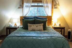 Un dormitorio con cama, dos mesitas de noche, una ventana con cortinas y un radiador.