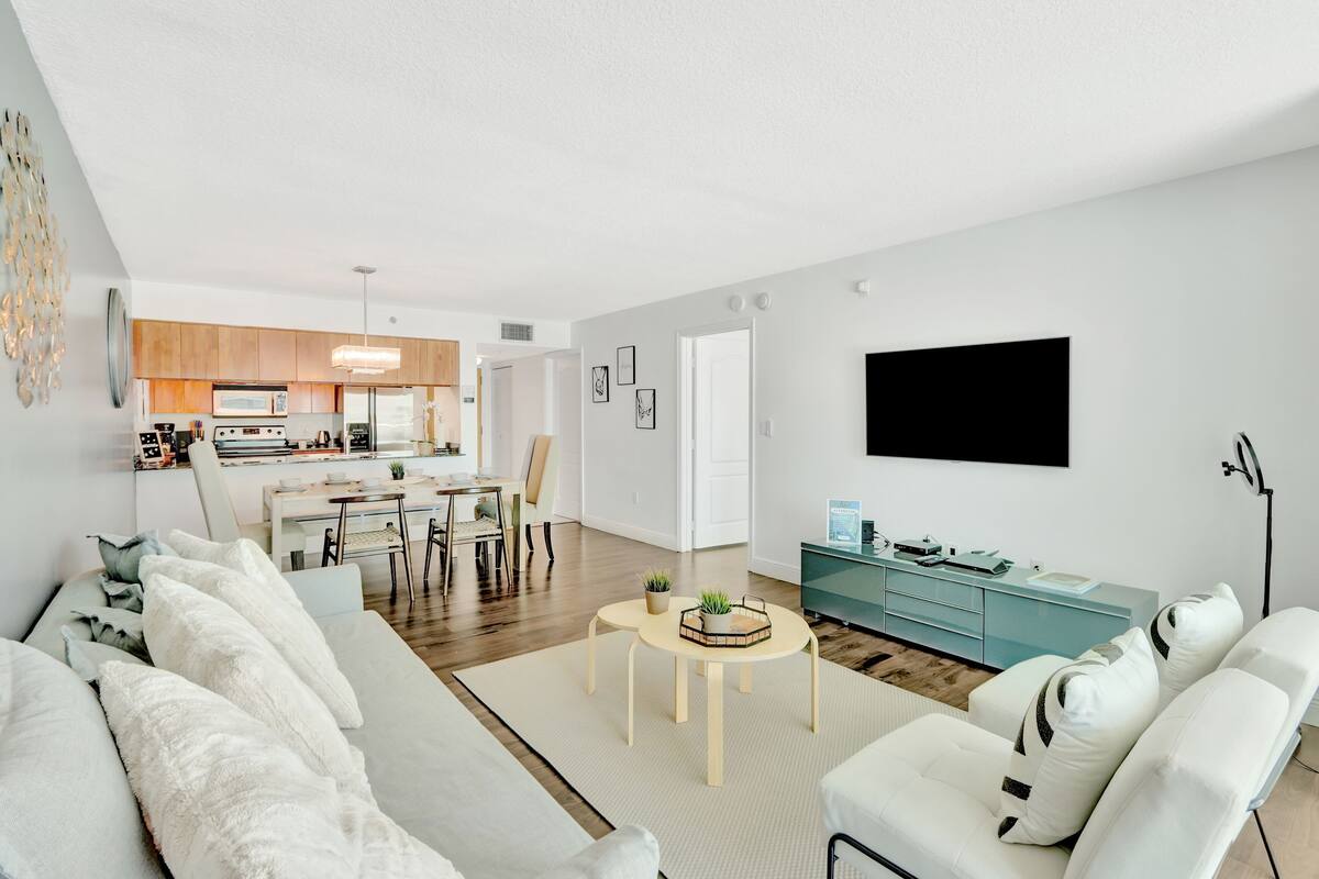 Uma sala de estar moderna com um sofá, uma mesa de centro e uma televisão na parede.
