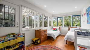 A child's bedroom with two beds, a wooden dresser, and a play area with toys and a toy truck.