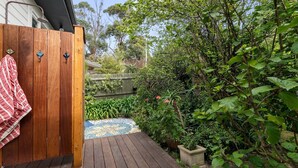A wooden deck with a tiled pathway leading to a wooden door with a towel hanging on it.