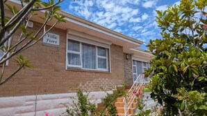 A two-story building with a brick facade, a sign reading "Villa Fiore", and a staircase leading to the entrance. - Villa Fiore- South Fremantle Retro Style (Beaconsfield)