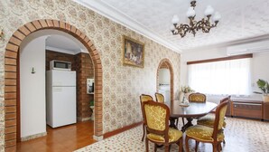 A dining area with a brick wall, a chandelier, and a dining table with chairs. - Villa Fiore- South Fremantle Retro Style (Beaconsfield)
