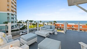 Un balcon avec des meubles d’extérieur, une vue sur l’océan et un immeuble doté de balcons.
