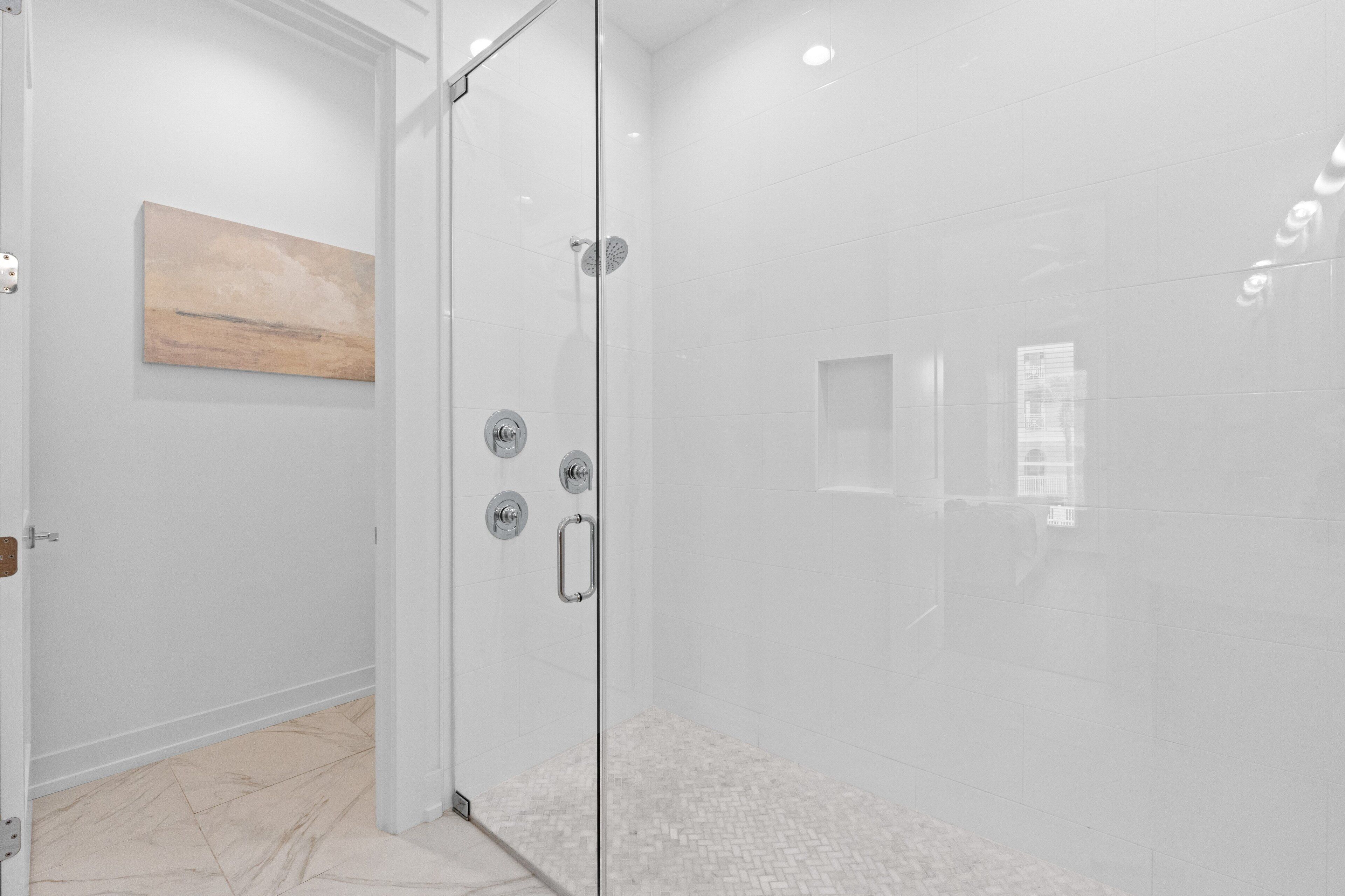 Un baño moderno con cabina de ducha de vidrio, una obra de arte de madera en la pared y suelo de baldosas.