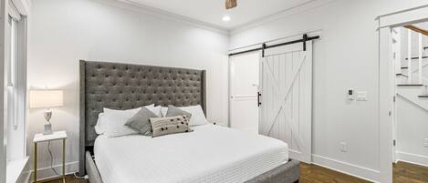 Un dormitorio con una cama grande, ventilador de techo, mesita de noche y armario con puerta corredera.
