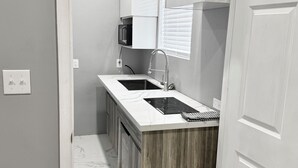 Une cuisine compacte dotée d’une cuisinière intégrée, de meubles blancs et d’un plan de travail en bois.
