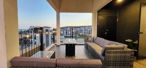 A balcony with a sofa, a small table, and a wicker basket.