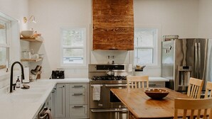 A modern kitchen with wooden cabinets, stainless steel appliances, and a wooden dining table.