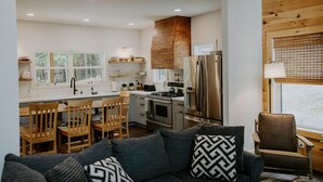 A modern kitchen with wooden cabinets, a stainless steel refrigerator, and a dining area with wooden chairs and a table.