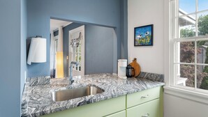 A modern kitchen with a granite countertop, a stainless steel sink, and green cabinets. - 1803 Historic Apartment in Heart of Salem•Steps to Haunted Happenings! (Salem)