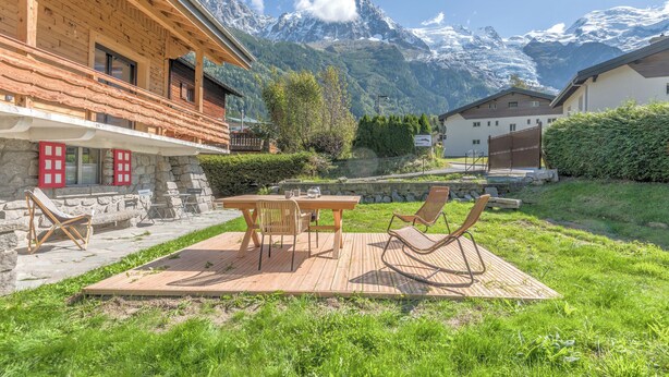 A wooden chalet with a deck, outdoor seating, and a mountain view. - Appartement Couttet - Welkeys (Chamonix-Mont-Blanc)