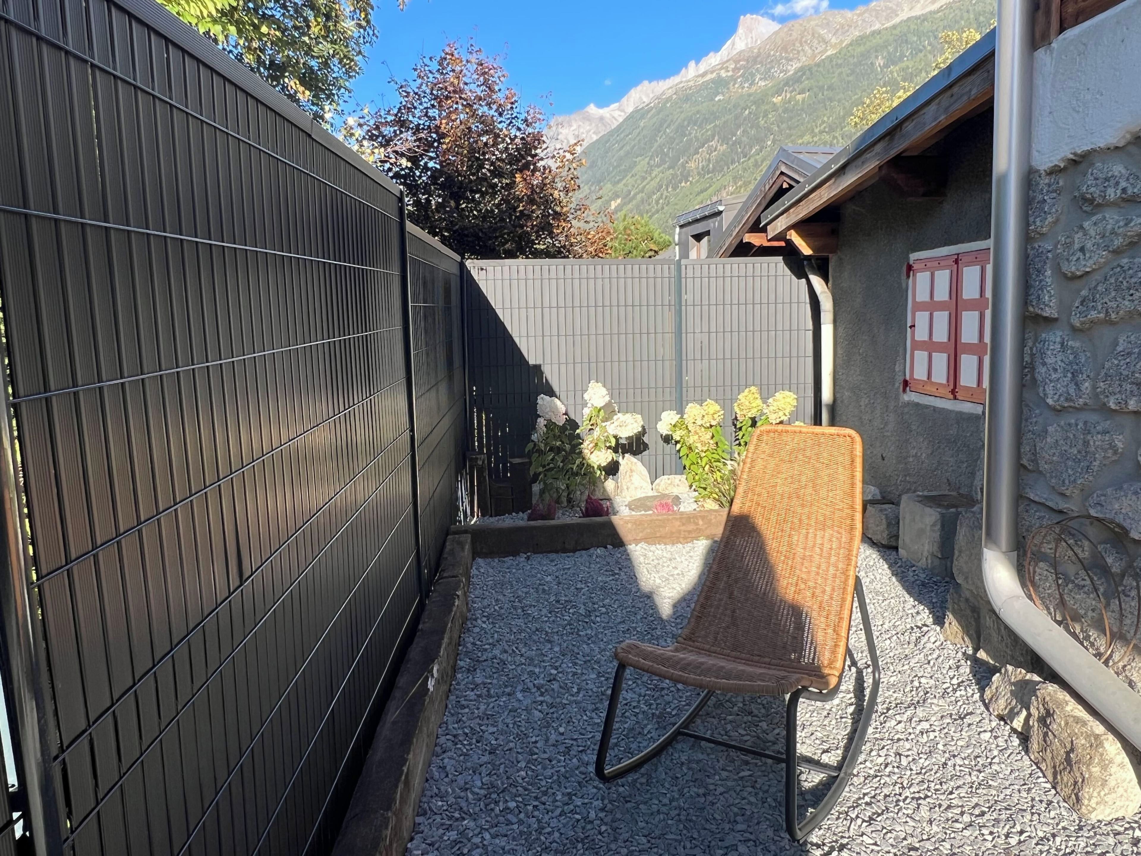 A patio area with a wicker chair, a stone wall, and a view of mountains.