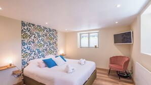A bedroom with a bed, a chair, a TV, and a window. - Appartement Couttet - Welkeys (Chamonix-Mont-Blanc)