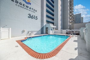 Area piscina con vasca azzurra cristallina, un edificio bianco con il numero 3615 e un design moderno.