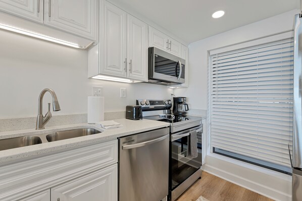 A modern kitchen with white cabinetry, stainless steel appliances, and a built-in microwave.