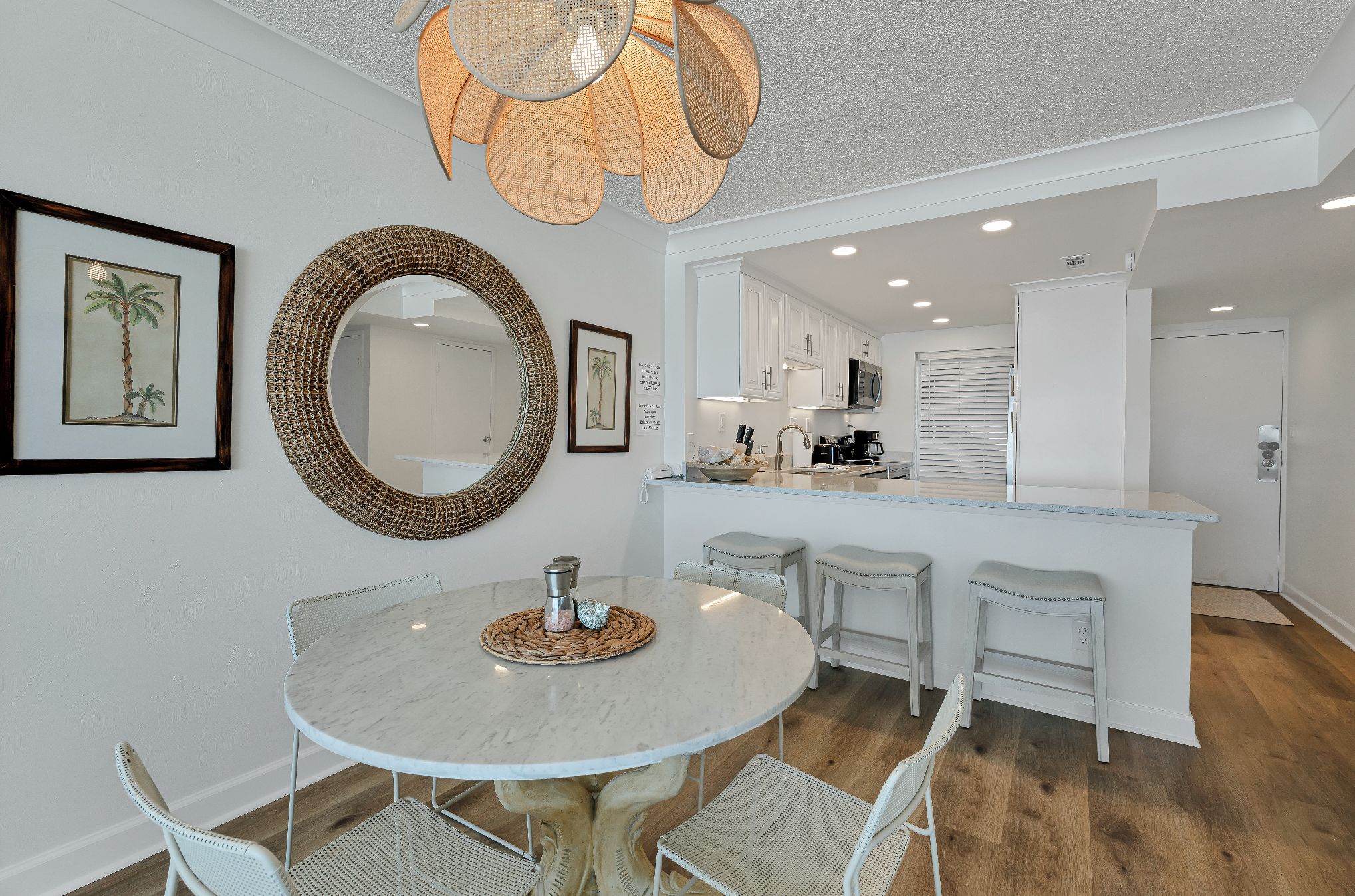 A modern kitchen with white cabinetry, a round dining table with chairs, and a decorative mirror on the wall.