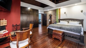 A bedroom with a large bed, wooden furniture, and a brick wall.