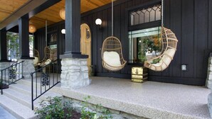 A covered porch with stone steps, wicker chairs, and hanging light fixtures. - Beauty on Beech HGTV Featured Designer Home (Nashville)