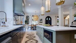 A modern kitchen with a large island, pendant lighting, and a patterned rug. - Beauty on Beech HGTV Featured Designer Home (Nashville)