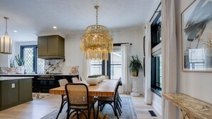 A modern kitchen with a dining area, featuring a large wooden table, black chairs, and a decorative chandelier. - Beauty on Beech HGTV Featured Designer Home (Nashville)