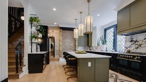 A modern kitchen with a central island, black cabinetry, and a marble backsplash. - Beauty on Beech HGTV Featured Designer Home (Nashville)