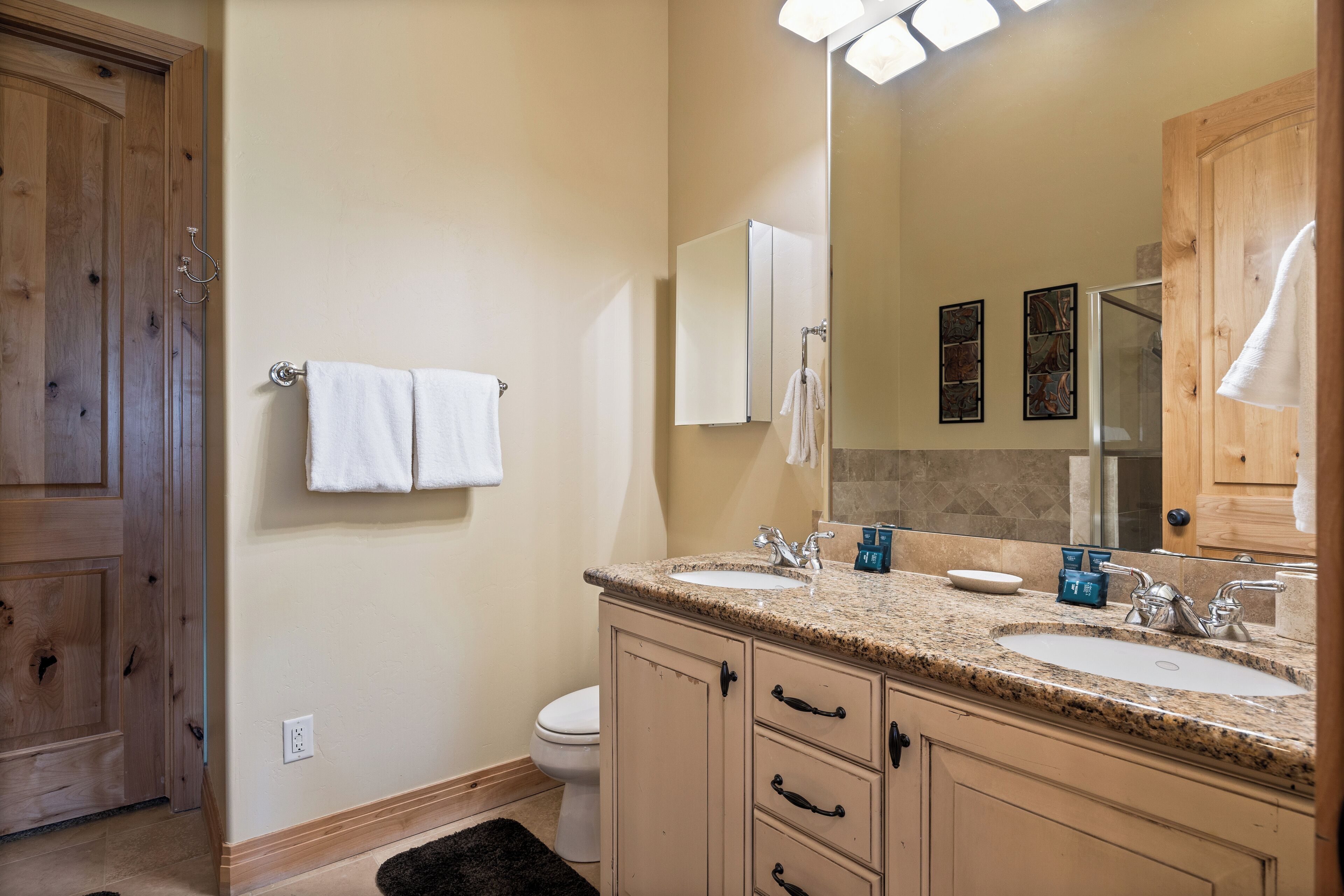 A bathroom with wooden cabinets, a double sink, and a large mirror.