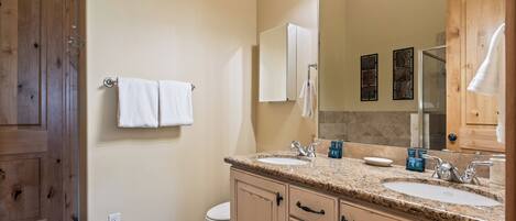 A bathroom with wooden cabinets, a double sink, and a large mirror.