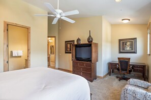 Une chambre d’hôtel avec un grand lit, une commode en bois avec un téléviseur, un bureau et une chaise.